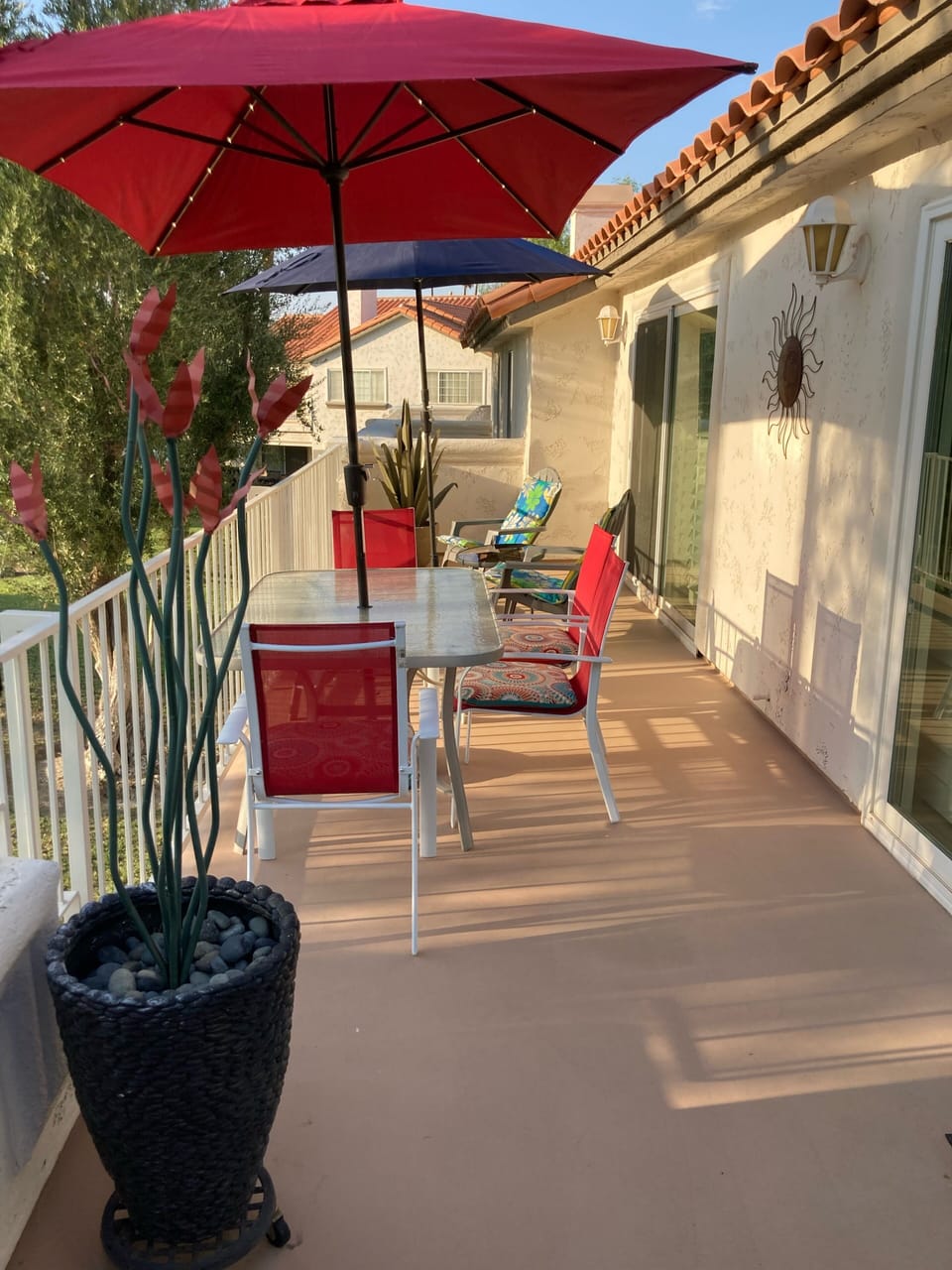 West facing rear balcony w/ large glass dining table and solar lighted umbrella.
