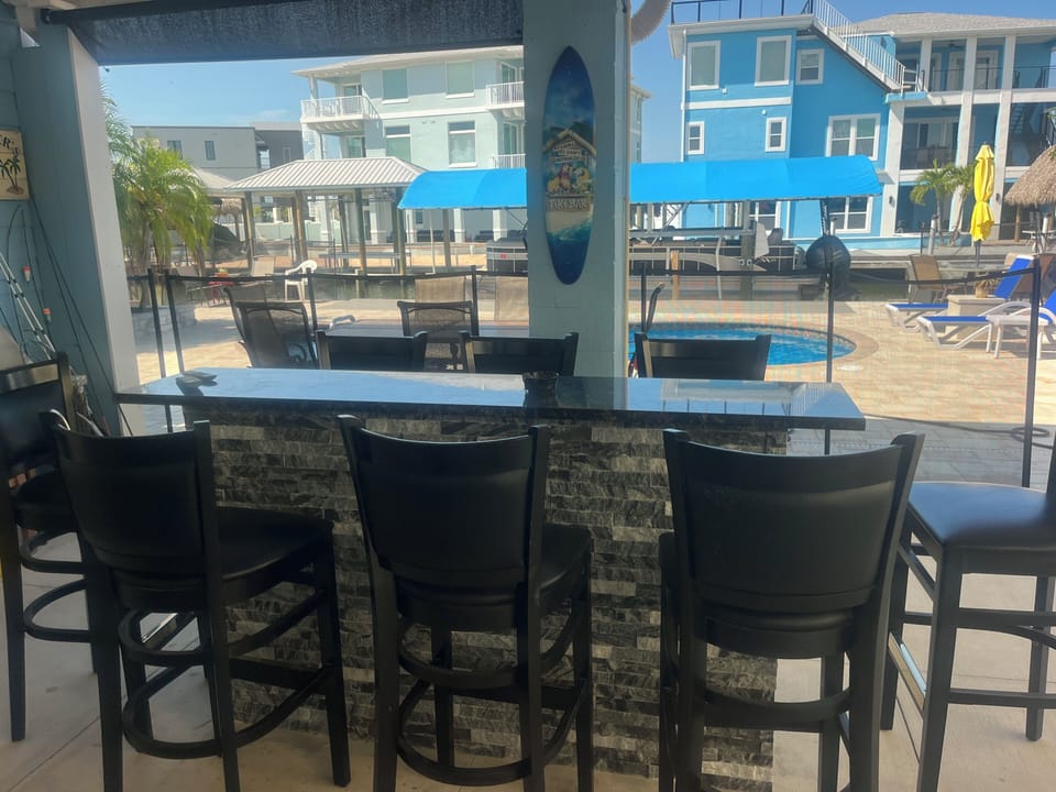 Bar next to pool with refrigerator, ice and TV.