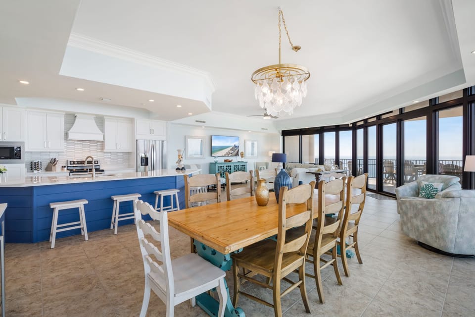 Dining table open to the kitchen & family room with floor to ceiling windows