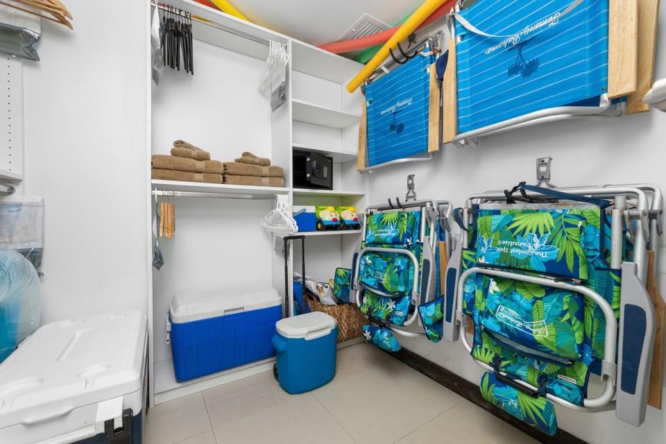 Primary walk-in closet with beach chairs, towels, coolers, and safe