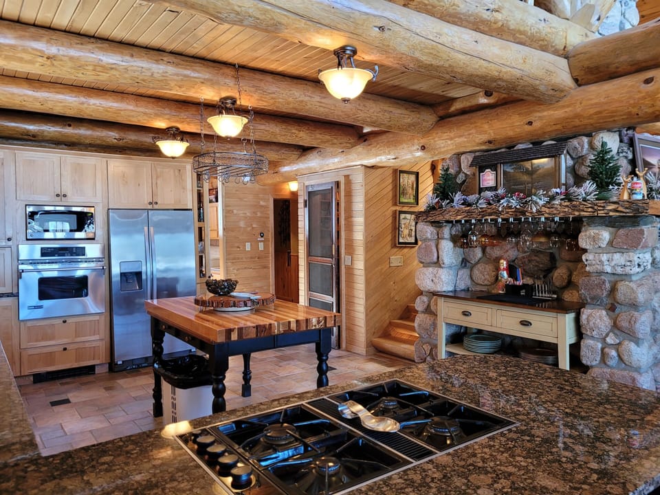 Kitchen and bar area with vaulted fireplace circling into dining and entryway