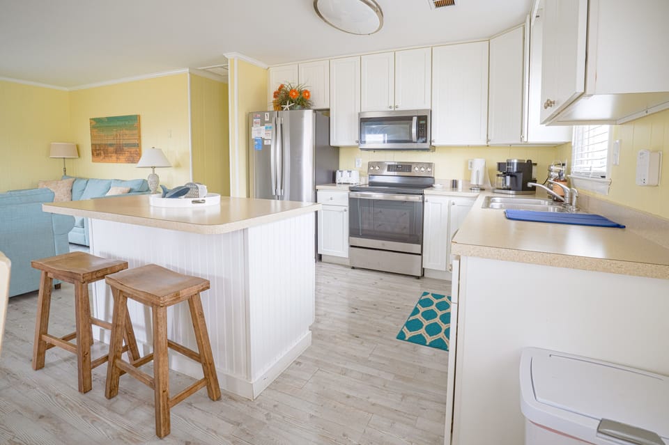 Kitchen with stainless steel appliances, electric range, microwave + dishwasher.