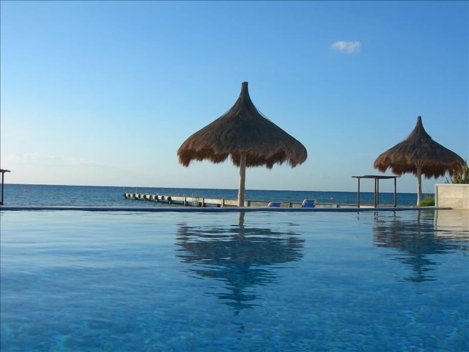 Swim in the infinity pool with the private pier and the Mexican Caribbean beyond