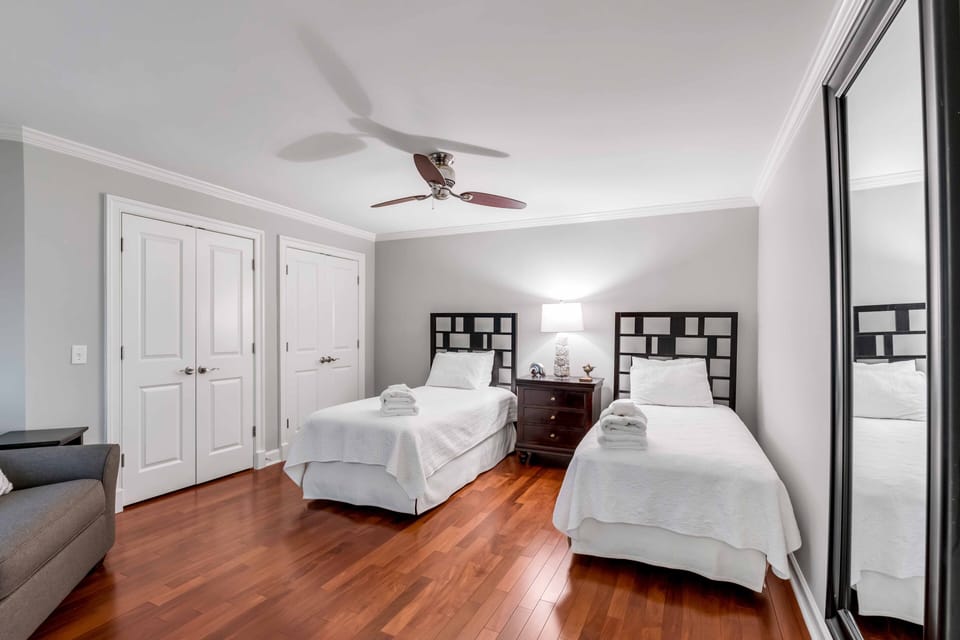 Relaxing beach-inspired bedroom featuring two twin beds and smart TV and ensuite bath with a bright, airy feel — short walk to the beach