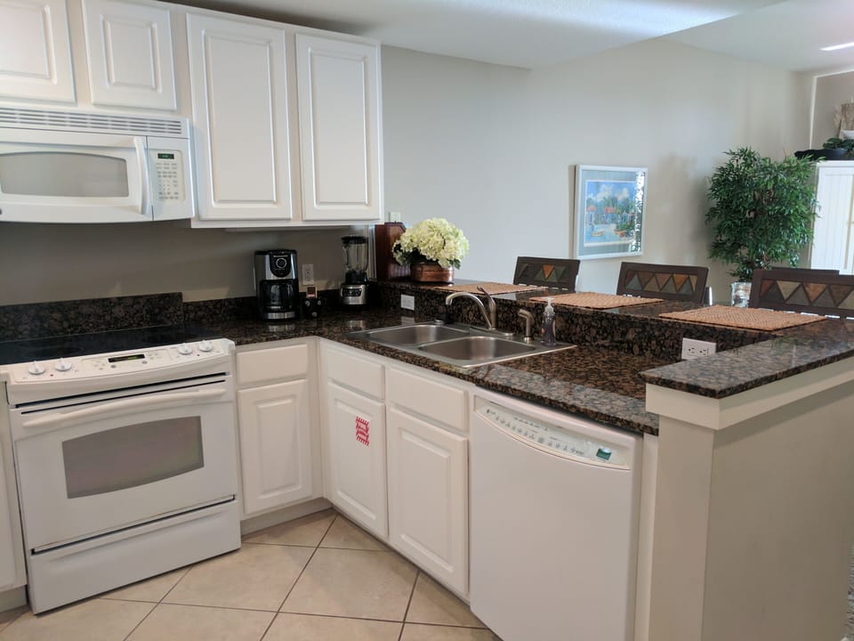 Kitchen with range & oven, microwave, fridge, coffee maker, blender, toaster.