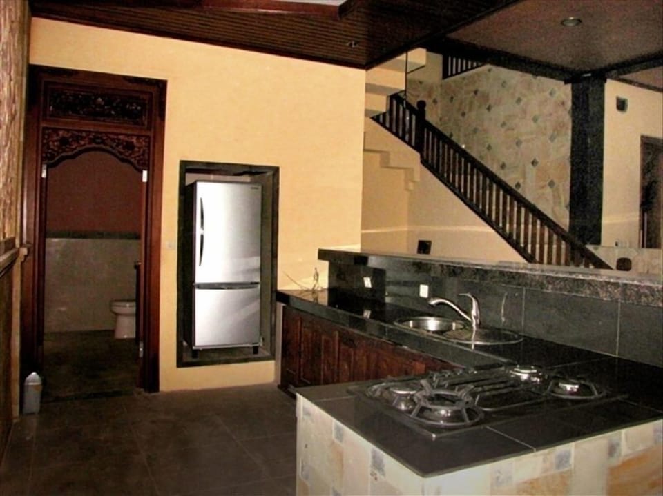 Kitchen with marble counter, teak cabinets, and stairway upstairs in the back 
