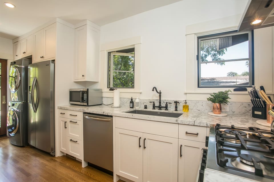Light filled kitchen with marble countertops and new appliances