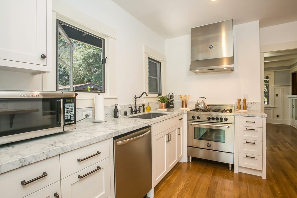 Light filled kitchen with marble countertops and new appliances