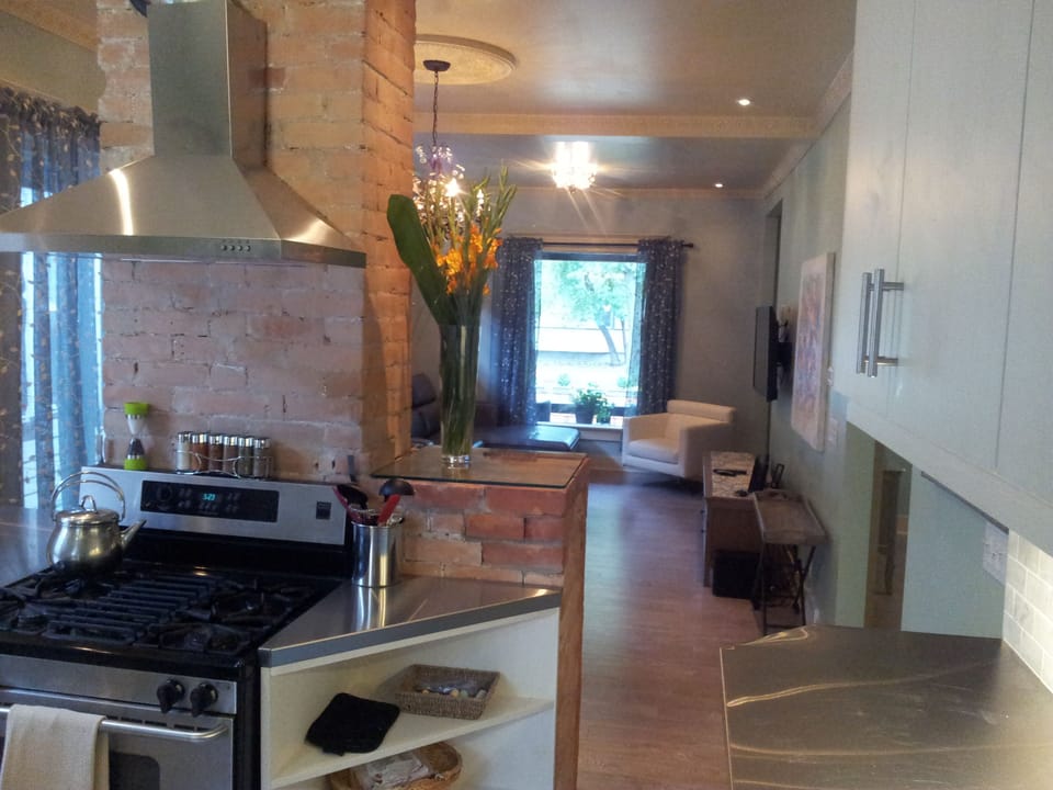 Stainless steel counters and gas stove sit against rustic original brick 
