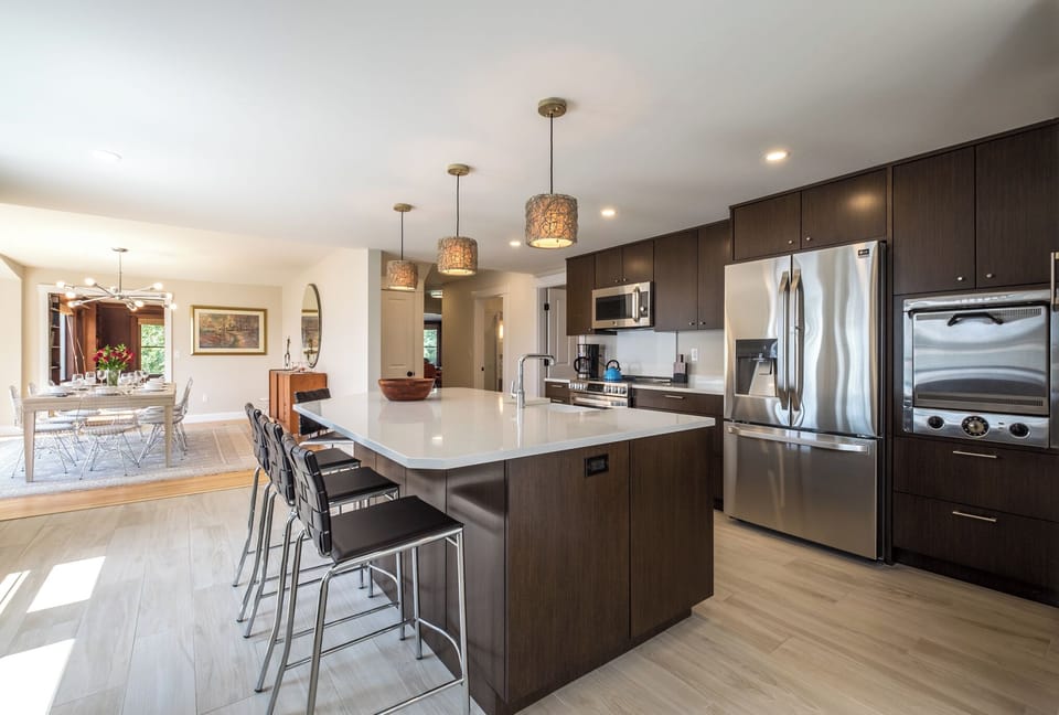 Kitchen island with 5 bar stools. Dining room and living room beyond.