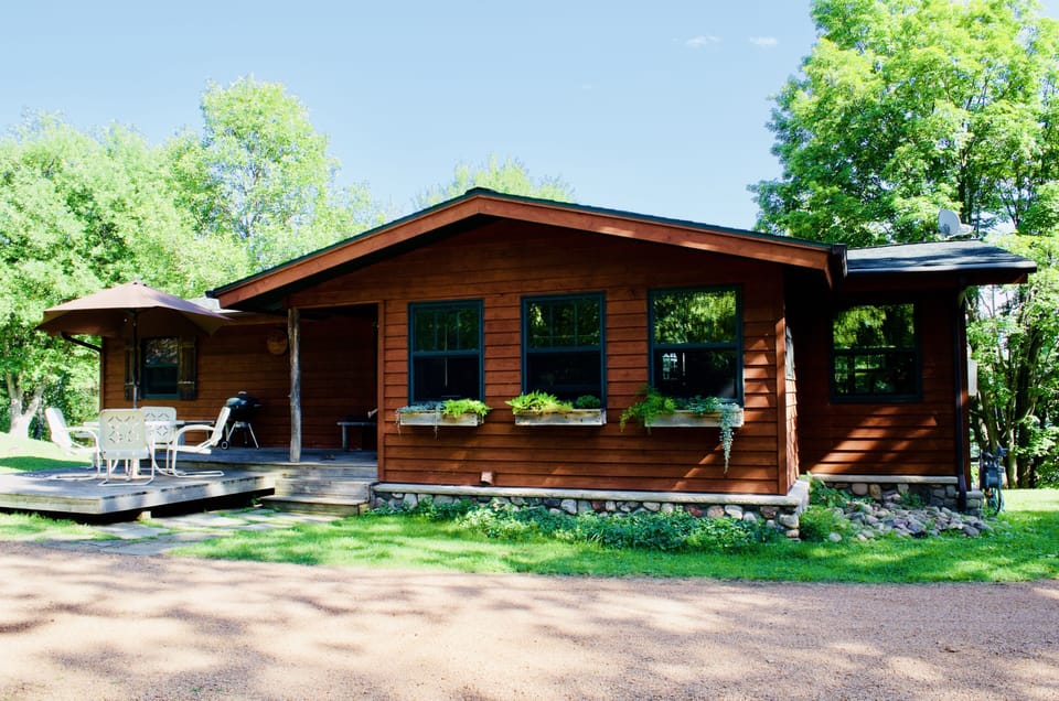 View of the front of the lodge and deck with patio set and charcoal bbq
