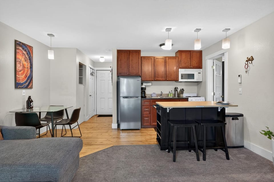 Kitchen area with cherry wood cabinets, stainless steel refrigerator, and a black island with wood countertop and stools.
