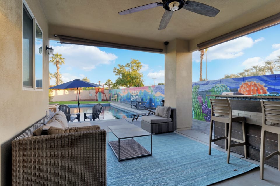 Patio has outdoor couch, rolling cooler, coffee and firepit table w/ 6 barstools