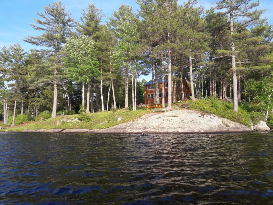 Looking at fire pit rock from a canoe on the Pond, house in background