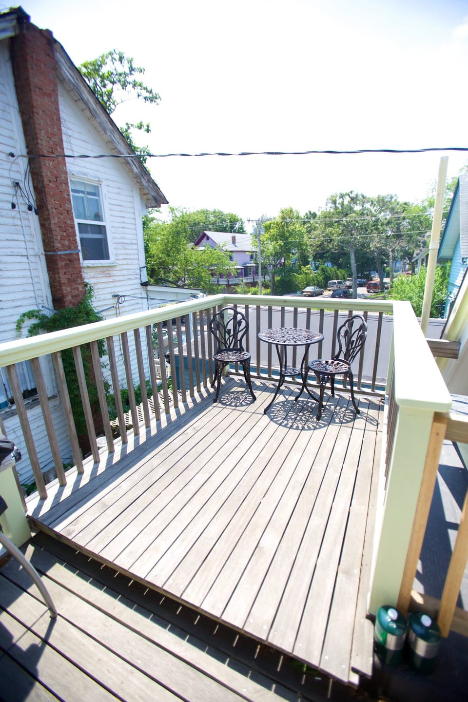 Small deck among the rooftops, with table, chairs and grill.