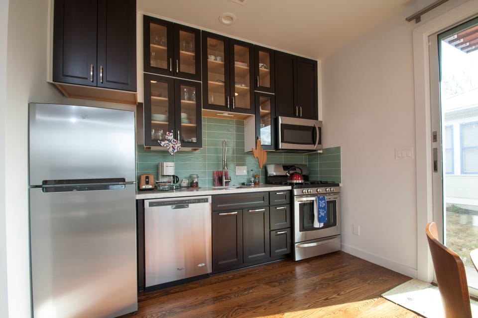 Well-stocked kitchen with silestone counter and glass backsplash