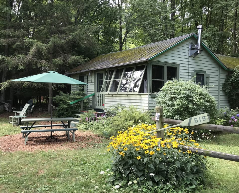 Summer cabin with daisies. 
Parking by split rail fence.
