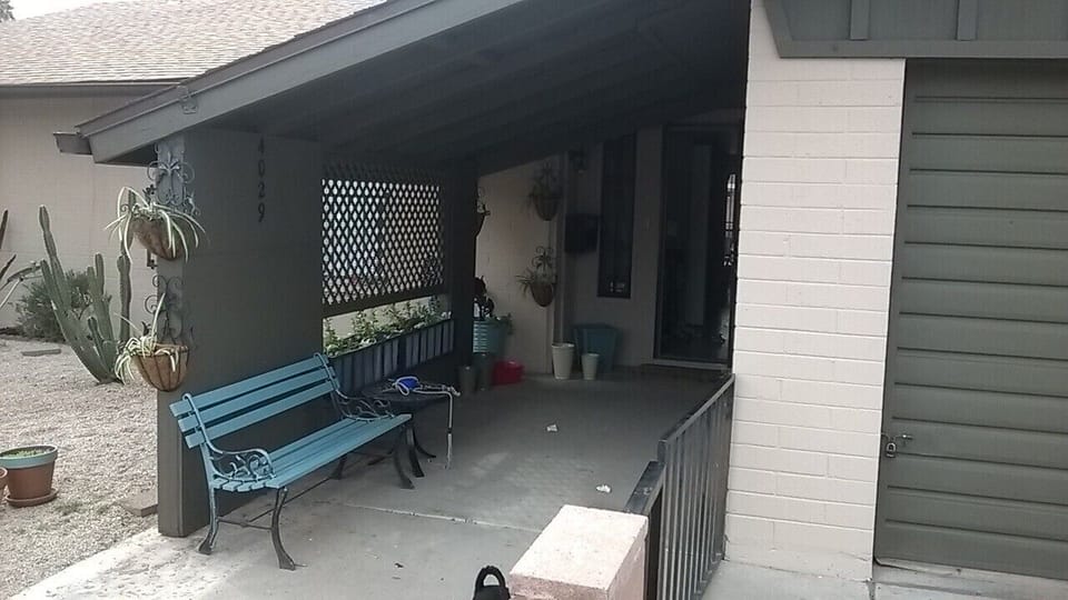 Covered patio in front of house with cozy seating.