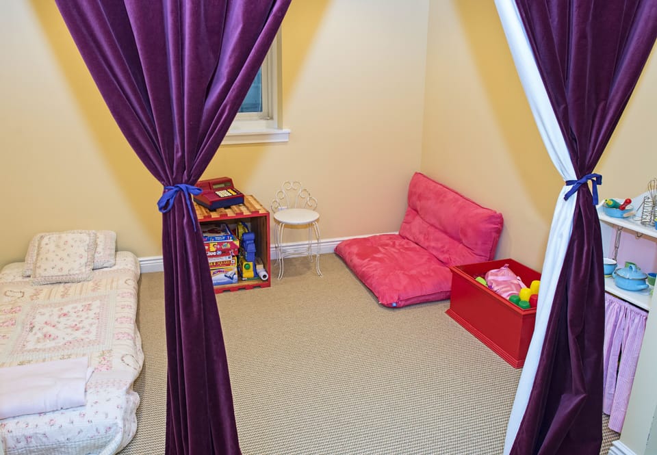Lower level play room.  Play kitchen, games, twin bed, toy box, futon.