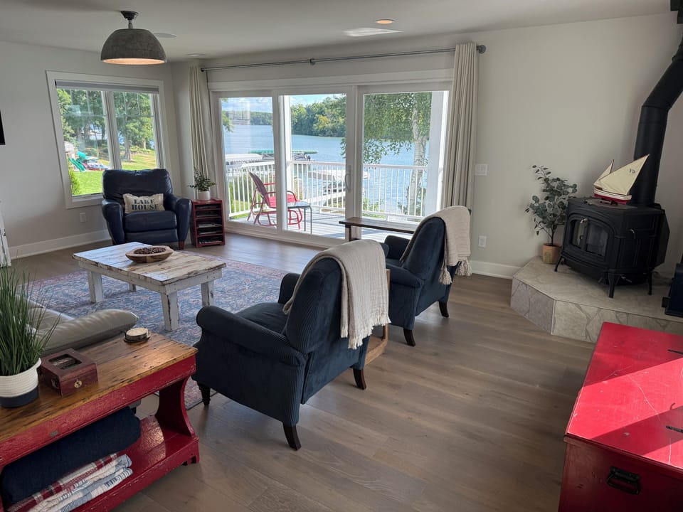 Living room with balcony and panoramic lake views and cast iron stove.