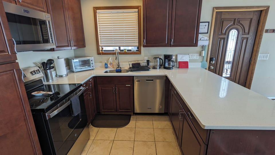 Fully stocked kitchen with stainless steel stovetop, oven, microwave, dishwasher