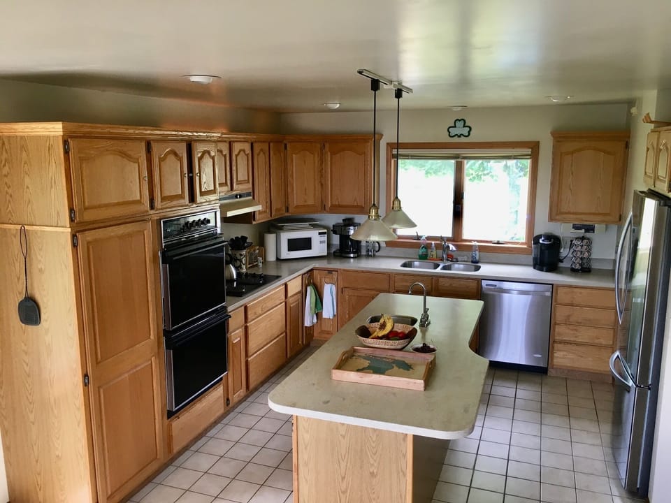 Large eat-in kitchen with double ovens, pots/pans, and cooking utensils. 