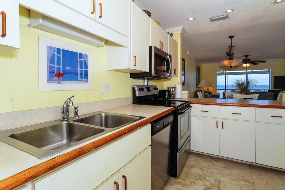 Fully equipped kitchen opens to living/dining area and window/door overlooking the bay and boat docks