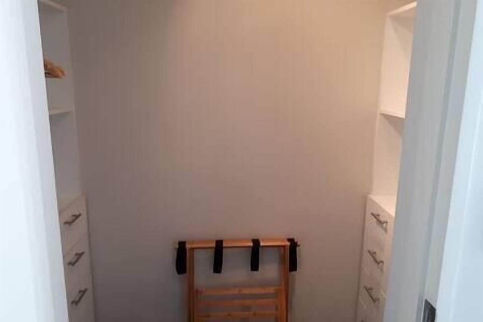 master bedroom walk in wardrobe with luggage rack and drawers 