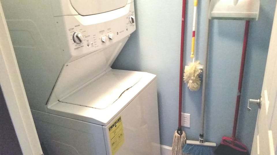Downstairs enclosed laundry room with stacked washer and dryer.