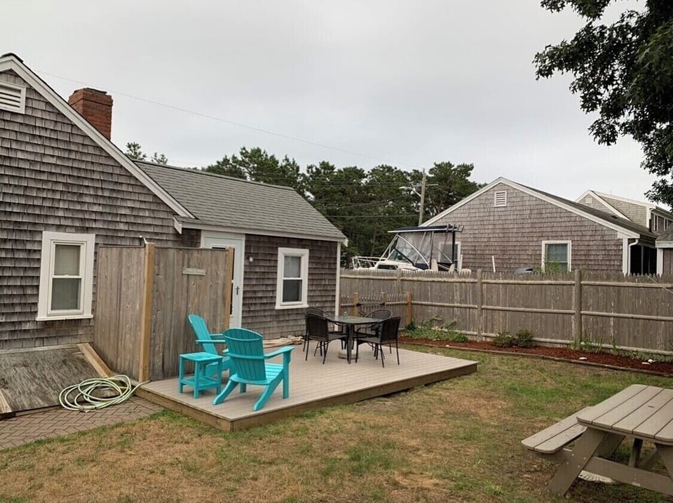 Back yard with deck, patio table and chairs, shower enclosure and picnic table.