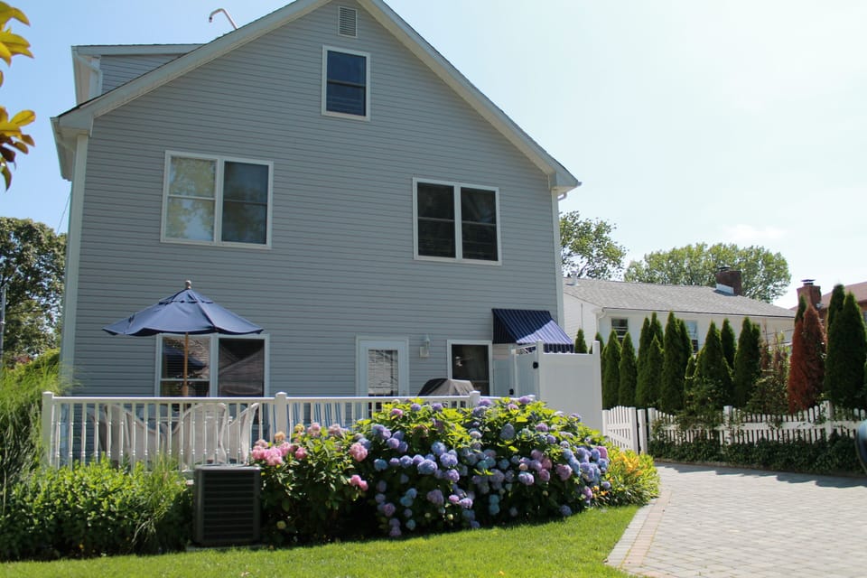 Back of house with grill and outdoor shower. Basketball hoop in driveway