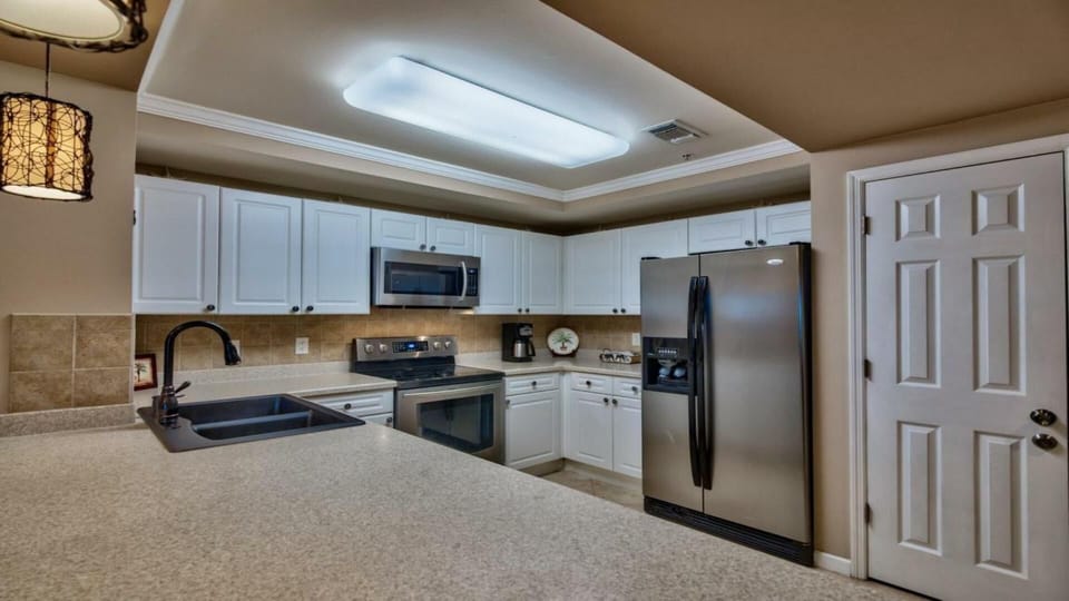 spacious kitchen with new appliances, sink, countertops, pendant lights.