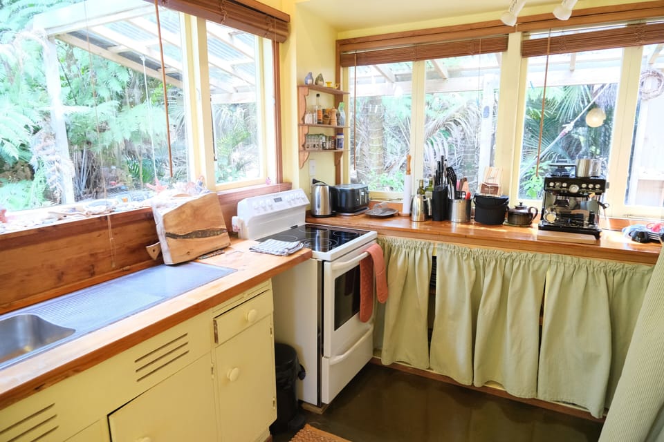 Kitchen with electric stove, fridge/freezer, microwave and coffee machine.
