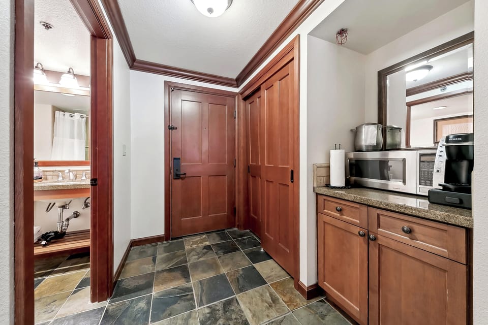 Mini fridge with small freezer inside cabinet below microwave.