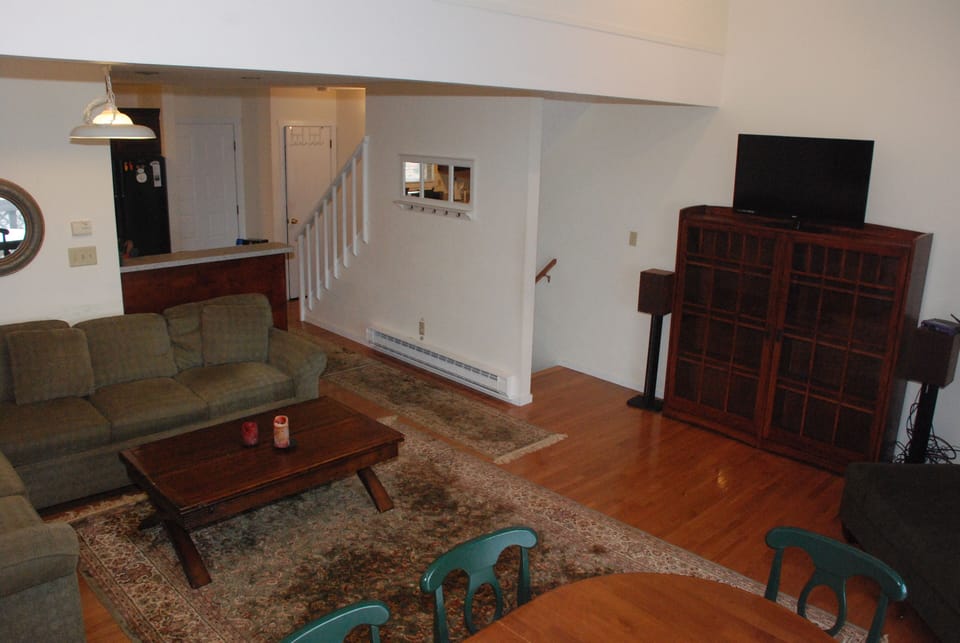 Second view of living room with view of stairways and entertainment center