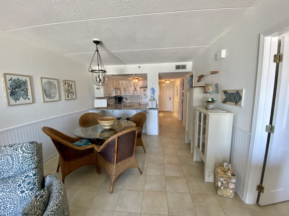Dining area has a table with four chairs & two barstools at the kitchen counter