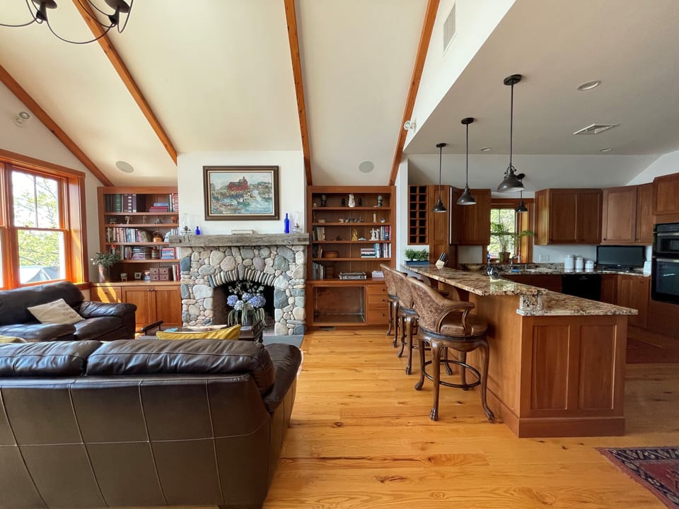 Lvrm w/stone fireplace, chef's kitchen and dining room(behind)