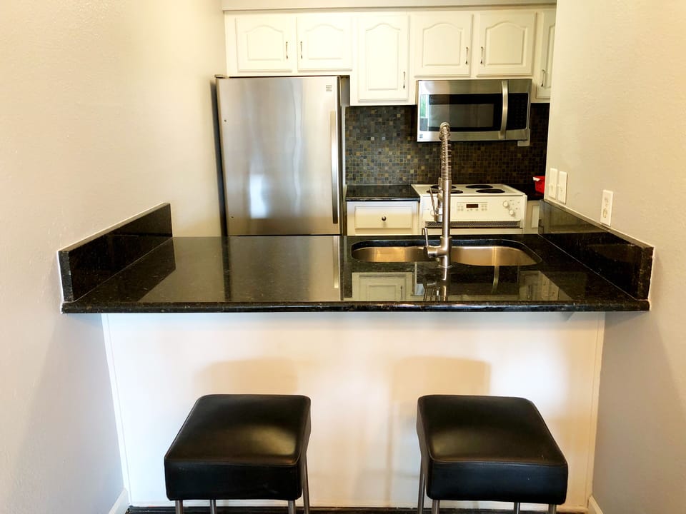 Dine-in kitchen with modern leather barstools, stainless, and granite.