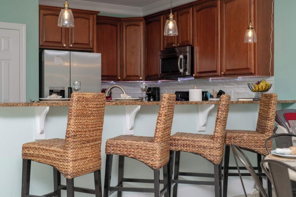 Pull up a seat and stay awhile! This kitchen island close-up shows off stylish bar chairs with comfy backs and a gleaming granite countertop—perfect for morning coffee, midday snacks, or late-night laughs.