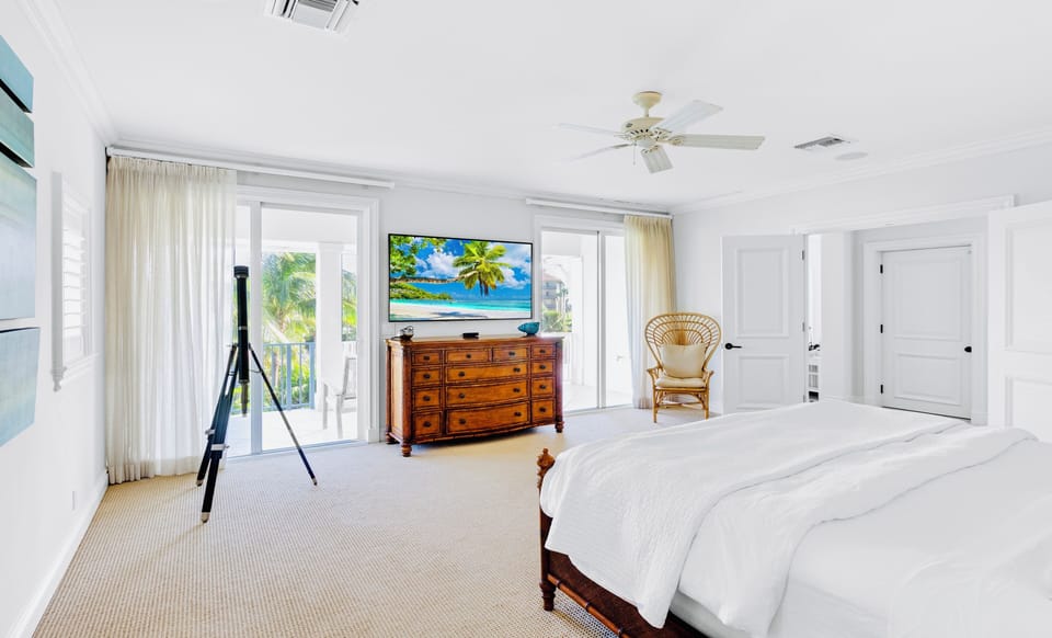 Spacious third-floor primary suite with king bed, TV and private balcony access
