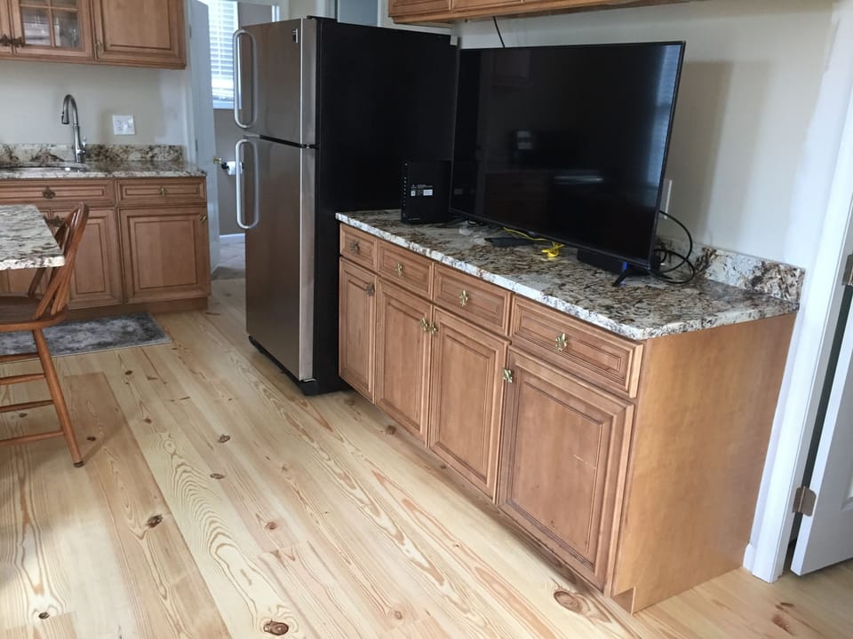 Living room, looking into kitchen area. Vaulted ceilings and pine hardwood floor