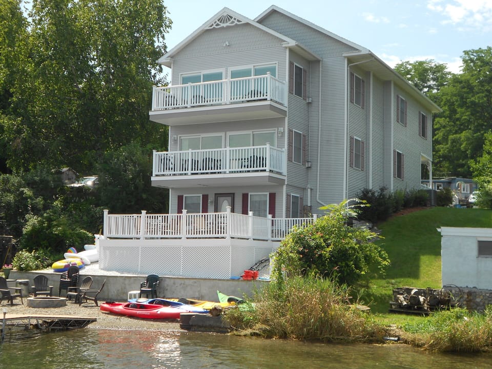View of house from lakeside with fire pit on beach