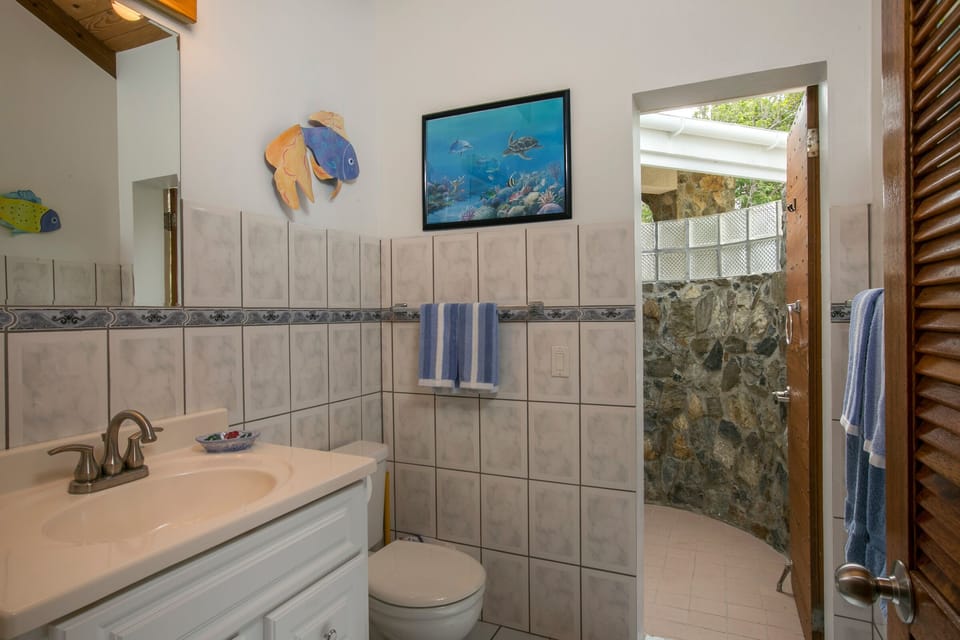 This en suite bath features a unique  outdoor local Caribbean stone shower!