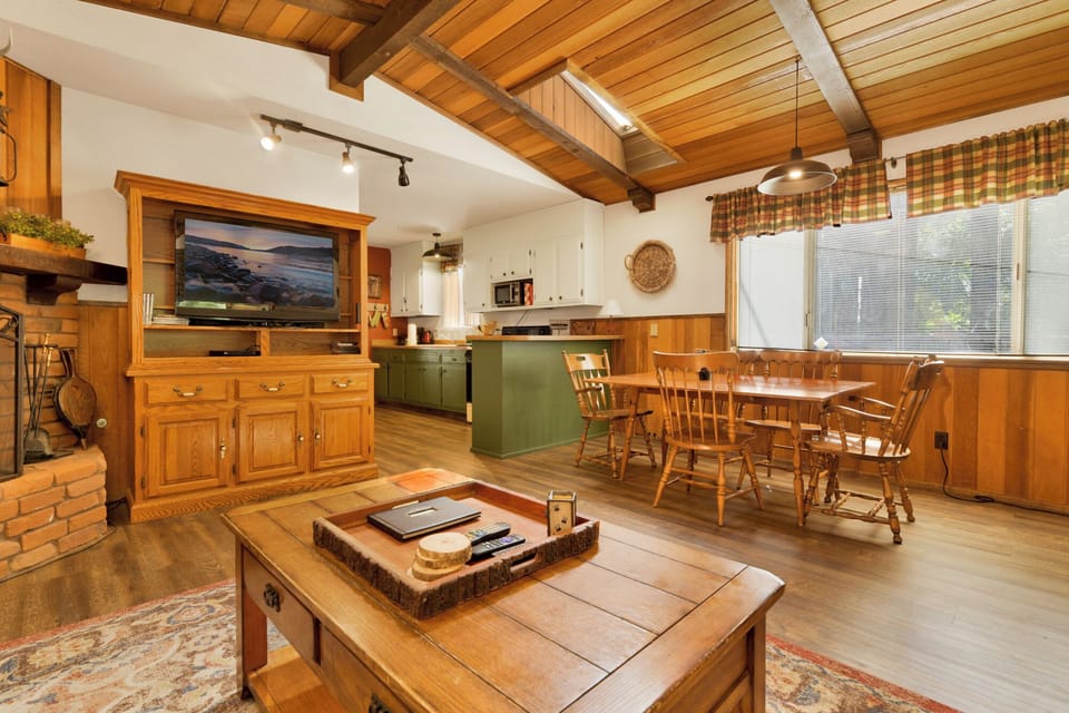 Cozy mountain living room with wood ceilings, stone fireplace, comfy seating, and smart TV—perfect for relaxing evenings, movie nights, and warm cabin vibes after outdoor adventures.