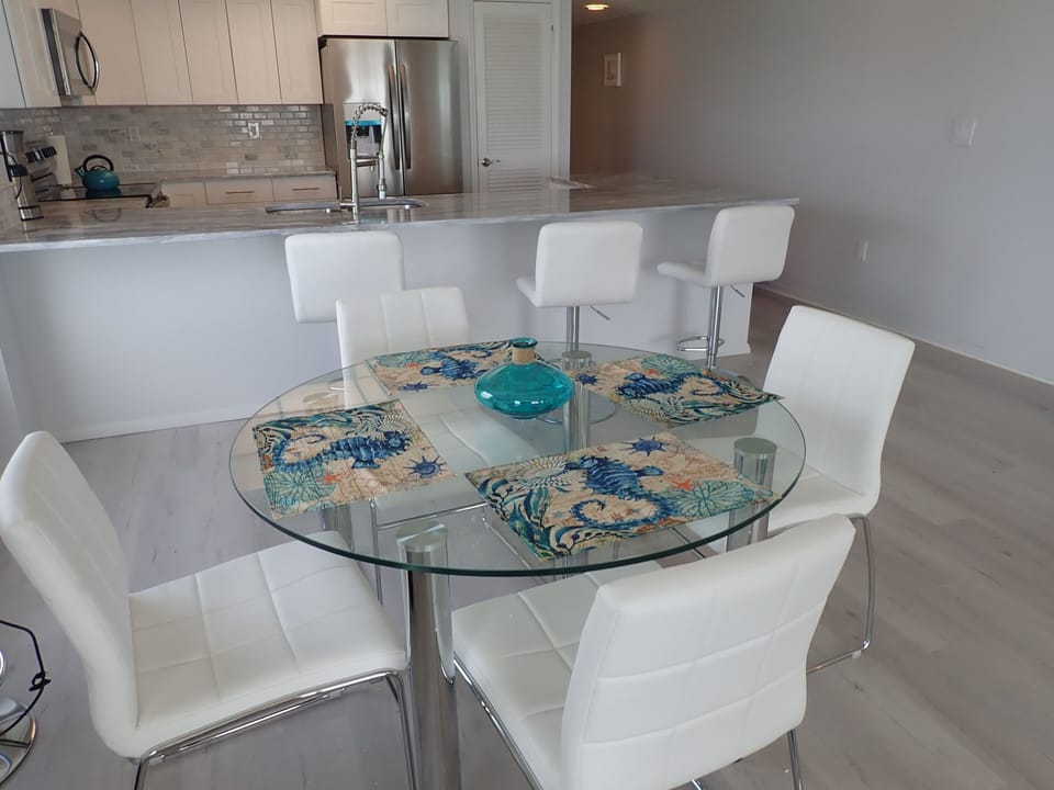 Dining area with 12 foot granite bar and 4 stools and matching table and chairs