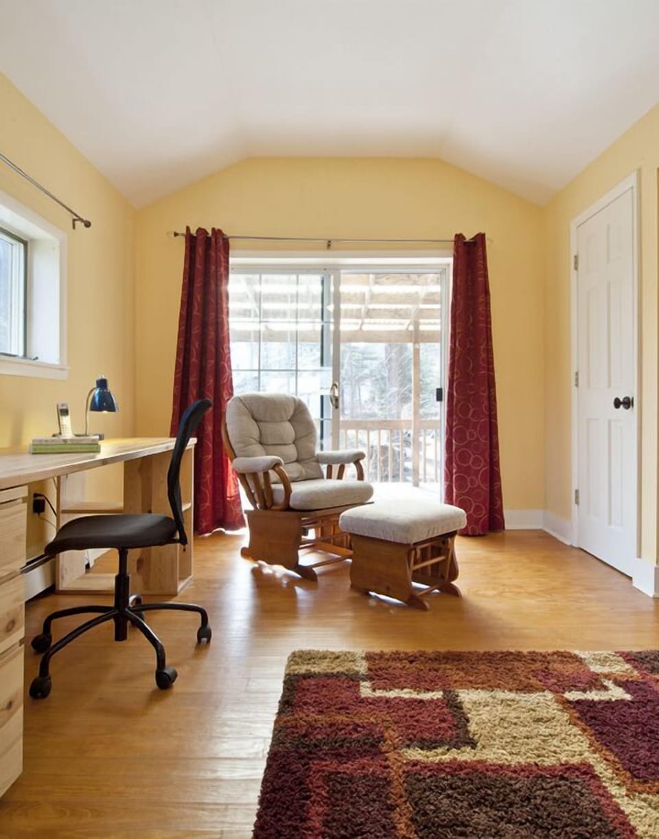 Sliding glass doors open onto a covered deck overlooking the stream.