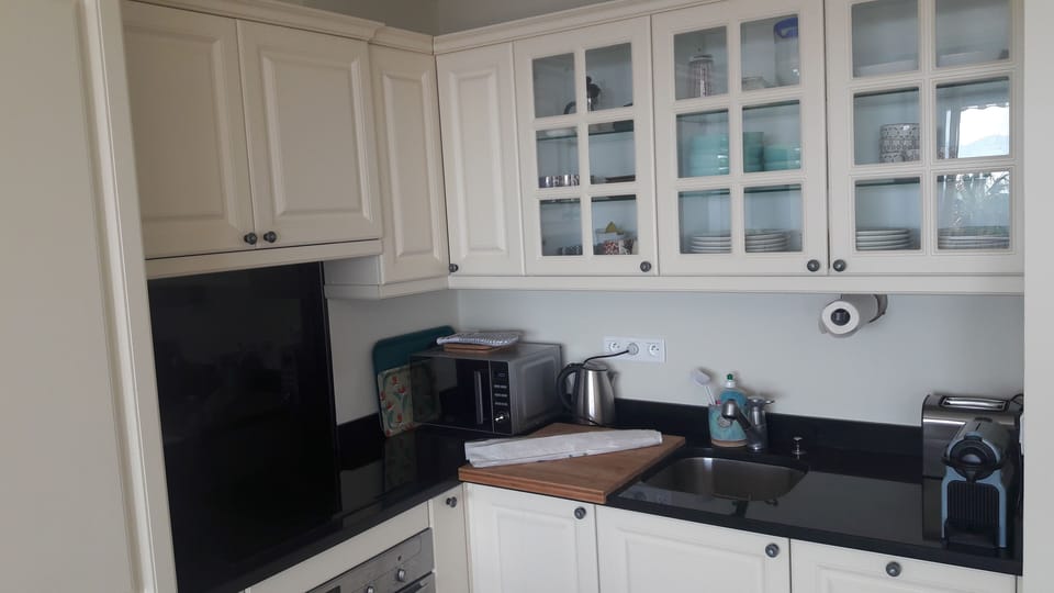 Kitchen with hob, oven, kettle, toaster, and a nespresso machine.