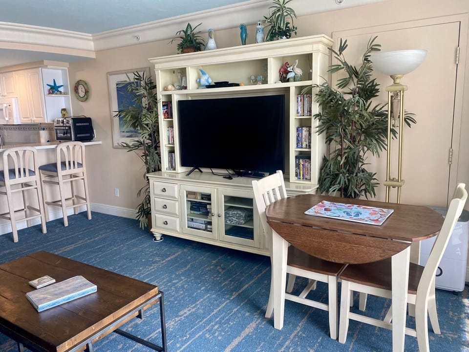 Modern living room with large flatscreen TV, tables, and chairs