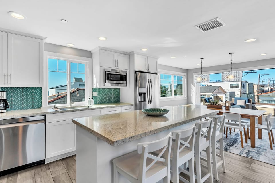 Fully stocked kitchen with everything needed for cooking, featuring premium appliances and an open layout with ocean views.