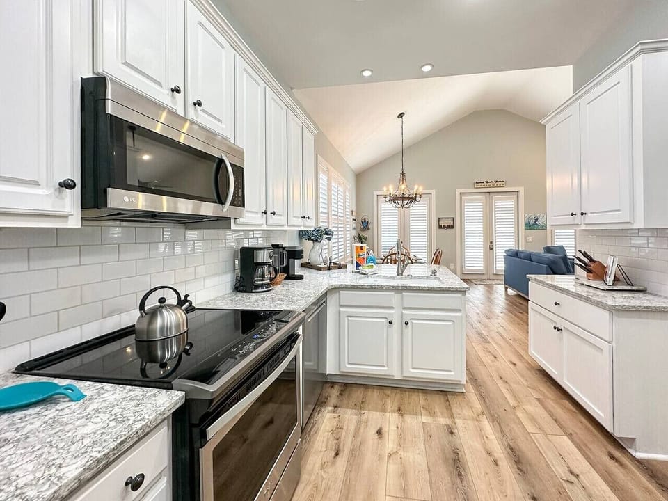 A bright, coastal kitchen featuring stainless steel appliances and generous counter space for easy meal prep and gathering.